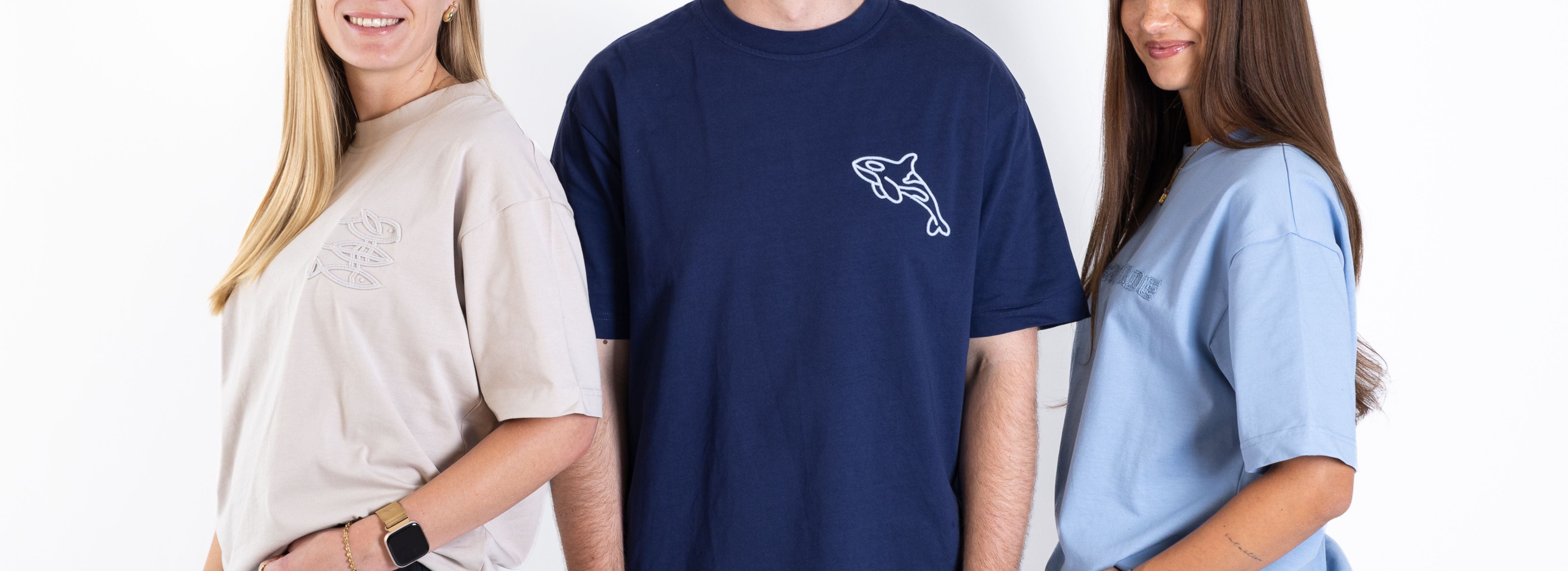 Werbebanner Stick-Kollektion: Drei Personen tragen Mission Erde T-Shirts mit geprägtem Logo-Print in Hellblau, Sand und Navy, u.a. "Cord Stick" und "3D Orca Stitch"